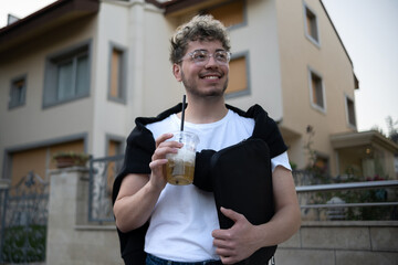 young and modern man standing in front of the villa with his cold drink