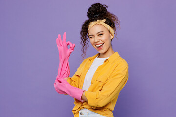 Young satisfied smiling fun happy woman wear yellow shirt rubber gloves while doing housework tidy...