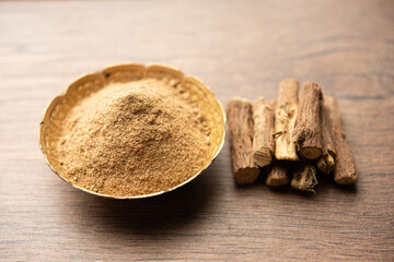 Ayurvedic Mulethi or Liquorice root stick or jeshthamadh powder served in a bowl over moody...