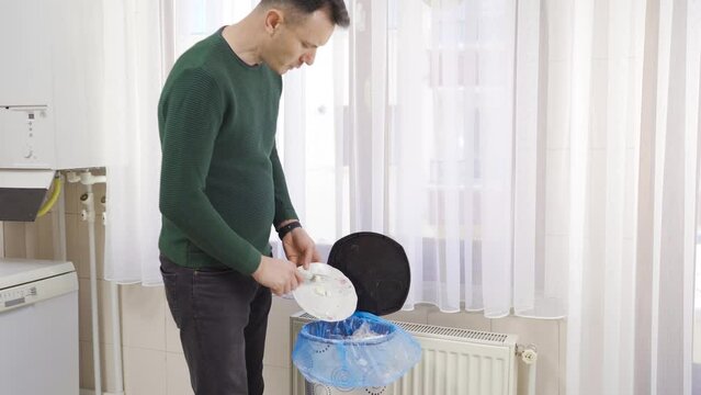Food waste or loss of food.
A man throws uneaten food from a plate into the trash.
