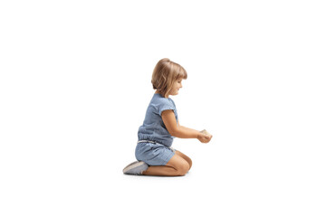 Profile shot of a little girl holding grain food in her hands and kneeling