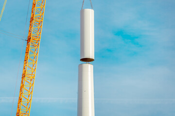 Obraz premium Building and assembling a construction windturbine by crane. Farmland with construction work at the windfarm, Wörrstadt, Germany. Energy crisis concept, wind turbine construction