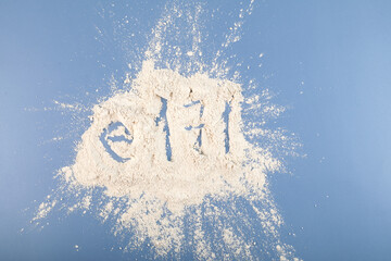 Titanium dioxide powder scattered on blue surface. TiO2 also known as titanium (IV) oxide or titania. Food additive, E171.  Inorganic compound, white chemical alimentary pigment - obrazy, fototapety, plakaty