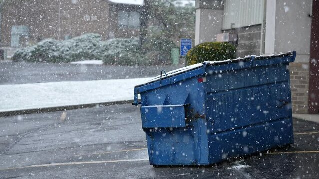 Early season snow storm in Utah as snowflakes fall looking at dumpster in slow motion.