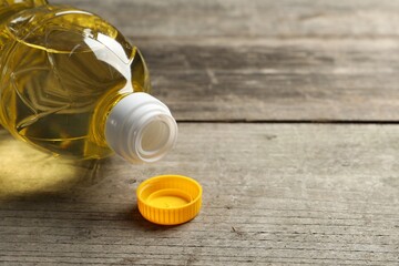 Plastic bottle of cooking oil on wooden table. Space for text