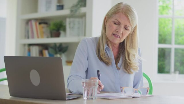 Forgetful menopausal mature woman working on laptop suffering with poor memory shot in slow motion