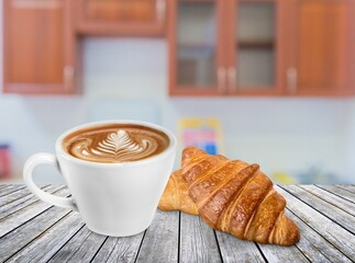 Tasty fresh croissant and cup of coffee on table