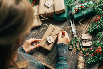 Unrecognizable woman wraps craft gifts for Christmas.