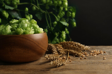 Fresh green hops, wheat grains and spikes on wooden table, space for text