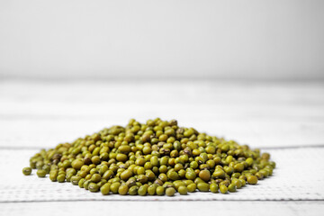 Pile of green mung beans on white wooden table, closeup. Space for text