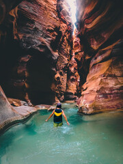 Female tourist walk in water in famous river canyon of Wadi Mujib in amazing golden light colors....