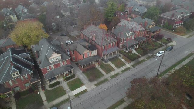 Drone aerial of urban houses in suburb surrounded by fog near edge of public park and city