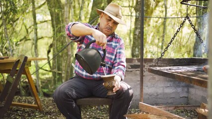 Ethnic man serving mate against barbecue rack in garden