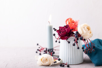 Romentic postcard. Tender colorful summer roses  flowers and widb fall berries and blue candle against textured wall. Selective focus. Still life. Postcard. Place for text. Banner. - 543292395
