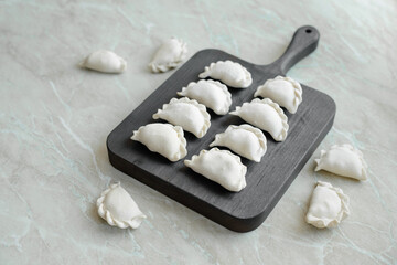 Beautiful raw stuffed dumplings on a wooden cutting board