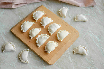 Beautiful raw stuffed dumplings on a wooden cutting board