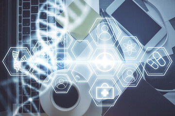 DNA hologram drawings over computer on the desktop background. Top view. Multi exposure. Concept...