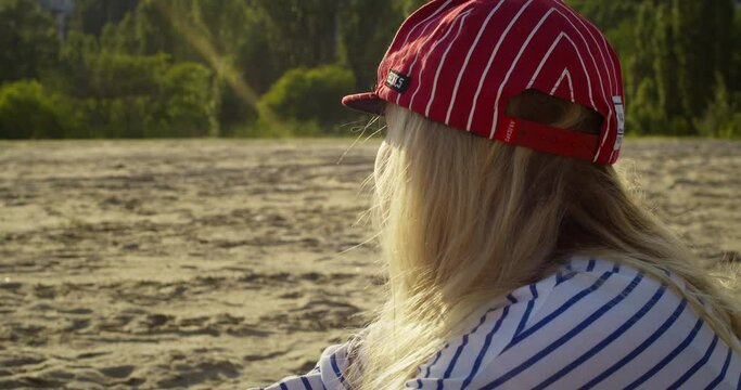 Rear view of woman on picnic on beach in summertime at sunset, medium shot