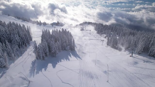 AERIAL Numerous working snow cannons making artificial snow at alpine ski resort. Modern technology for preparing good skiing conditions and prolonging winter season. Wintertime in mountain ski area.
