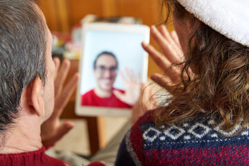 Christmas family video call. Parents waving to son in tablet