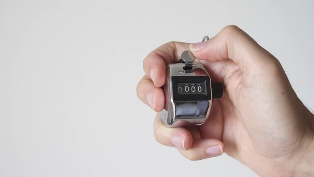 Hand with metal tally counter going from 9999 to 0000