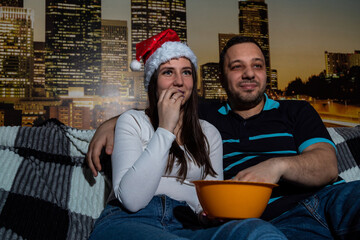 Woman and man are smiling, watching movie, eating popcorn. Selective focus. Picture for website about family, movies, Christmas.