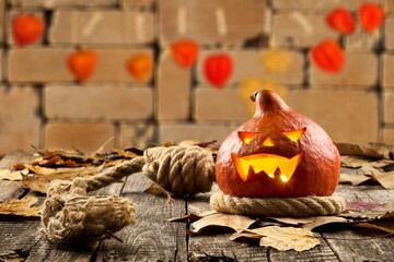 Scary pumpkin with carved face glowing with Halloween decor.