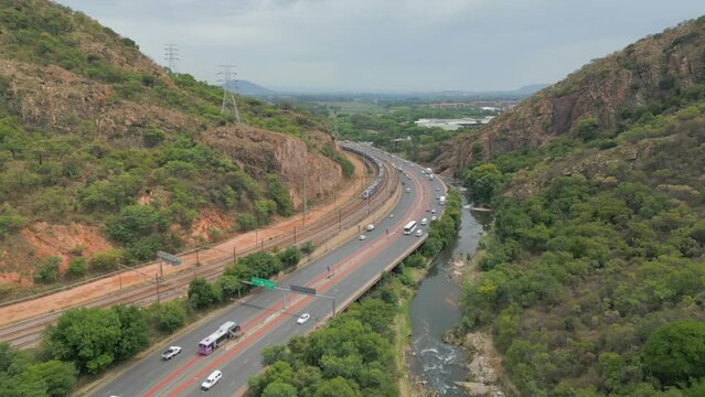Aerial: Train and road traffic travel through Wonderboompoort near Pretoria North