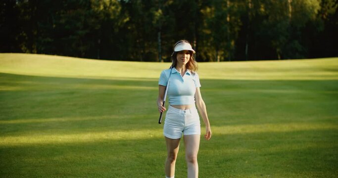 A young female golfer is walking along the golf course. . High quality 4k footage