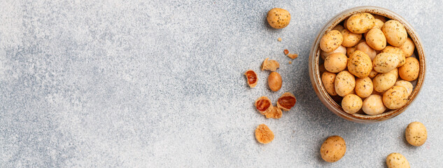 Crispy Nuts. Peanuts in glaze with seasonings and spices. A delicious snack for beer. Grey concrete background. Selective focus, top view, copy space, banner