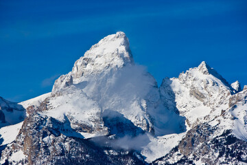 Snow covered Grand Teton Mountains near Jackson Wyoming with cloud and blue sky