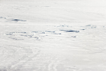 Fototapeta na wymiar Deep snow forms ridges from a wind blown storm on a frozen winter field.
