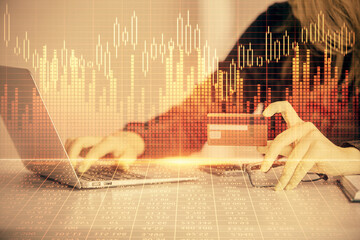 Double exposure of woman on-line shopping holding a credit card and financial graph drawing. Stock market E-commerce concept.