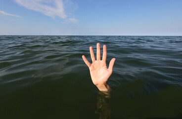 hand on the sea  of a person who is drowning and seeks help