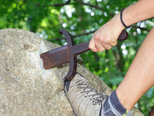 hand of the man who forcibly tries to extract the sword Excalibur is stuck in the rock like King Arthur