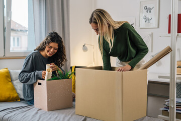 european female students unpacking in dorm room - obrazy, fototapety, plakaty