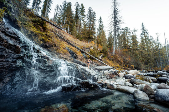 Horizontal image of Woman walking near cascading hot waterfalls to  enjoy the thermal healing waters geothermal hot springs in nature in the back country of Idaho USA.
