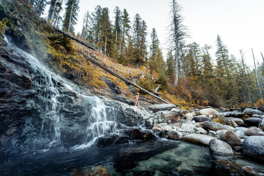 Horizontal image of Woman walking near cascading hot waterfalls to  enjoy the thermal healing waters geothermal hot springs in nature in the back country of Idaho USA.