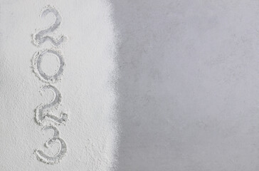 The numbers 2023 are handwritten on scattered flour on a gray stone surface. View from above....