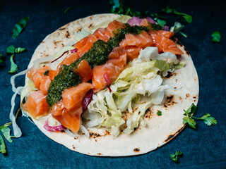 Healthy breakfast concept. Salmon, lettuce, herbs and pesto sauce on a tortilla. Tasty food in restaurant. Close-up.