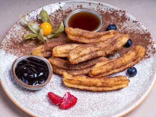 Close-up of a sweet dessert in a restaurant. Choux pastry sticks. Caramel and chocolate sauce.