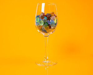 colored stones in glass in jar in bucket on orange background