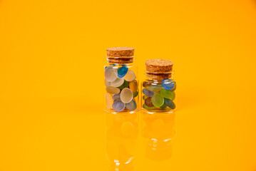 colored stones in glass in jar in bucket on orange background