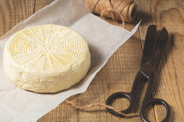 homemade wheel of cheese on wooden table.