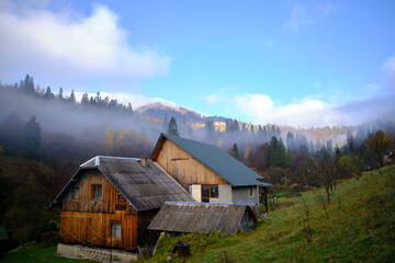 Fototapeta na wymiar A wooden house in the mountains covered with fog