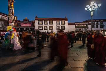 LHASA, CHINA: Tibetan pilgrims walking in Barkhor square at night and Jokhang temple in the background