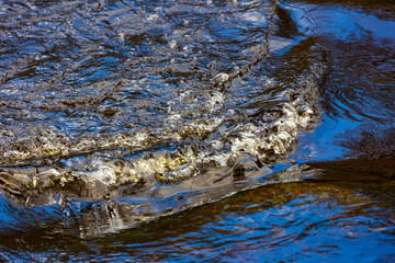 Running river rapids with blue sky reflection
