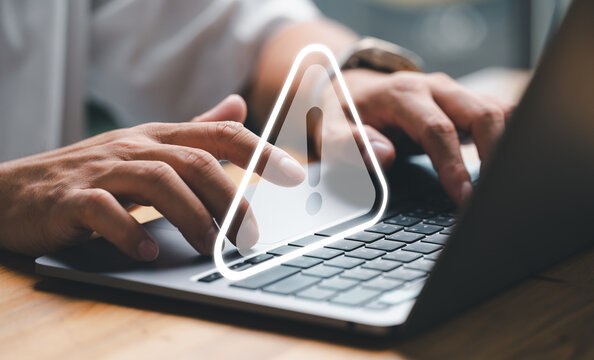 User or developer working on laptop computer with triangle caution warning sign for notification error and maintenance concept, computer virus detected, personal data protection, network security.