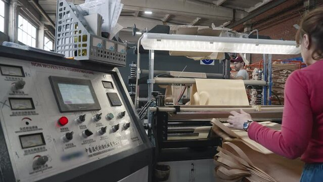 Reusable shopping bags manufacturing process at the industrial facility. Automated equipment deals with shopping bags manufacturing. Manufacturing shopping bags with sustainable material.