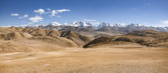 FRIENDSHIP HIGHWAY, TIBET, CHINA: dry yellow winter landscape and snowy mountain range, on the road...